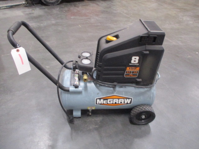 A gray and black air compressor on the ground